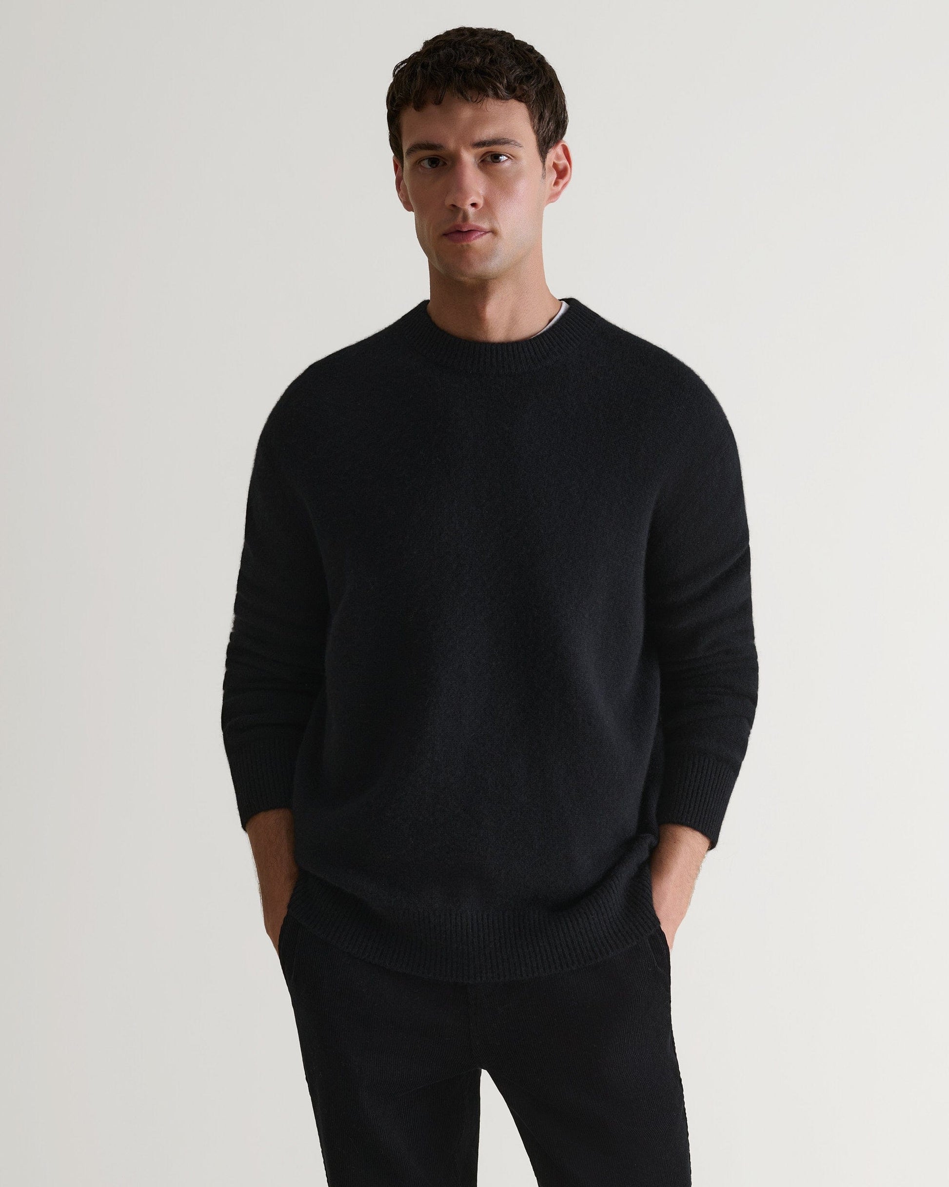 Image 1 of 7 showing man wearing Rise & Fall's Finest Cashmere Mid-Weight Crew Neck Jumper in black with tailored black trousers.