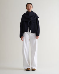 Image 1 of 7 showing woman wearing Rise & Fall's navy cashmere wool double faced scarf jacket with white jeans.