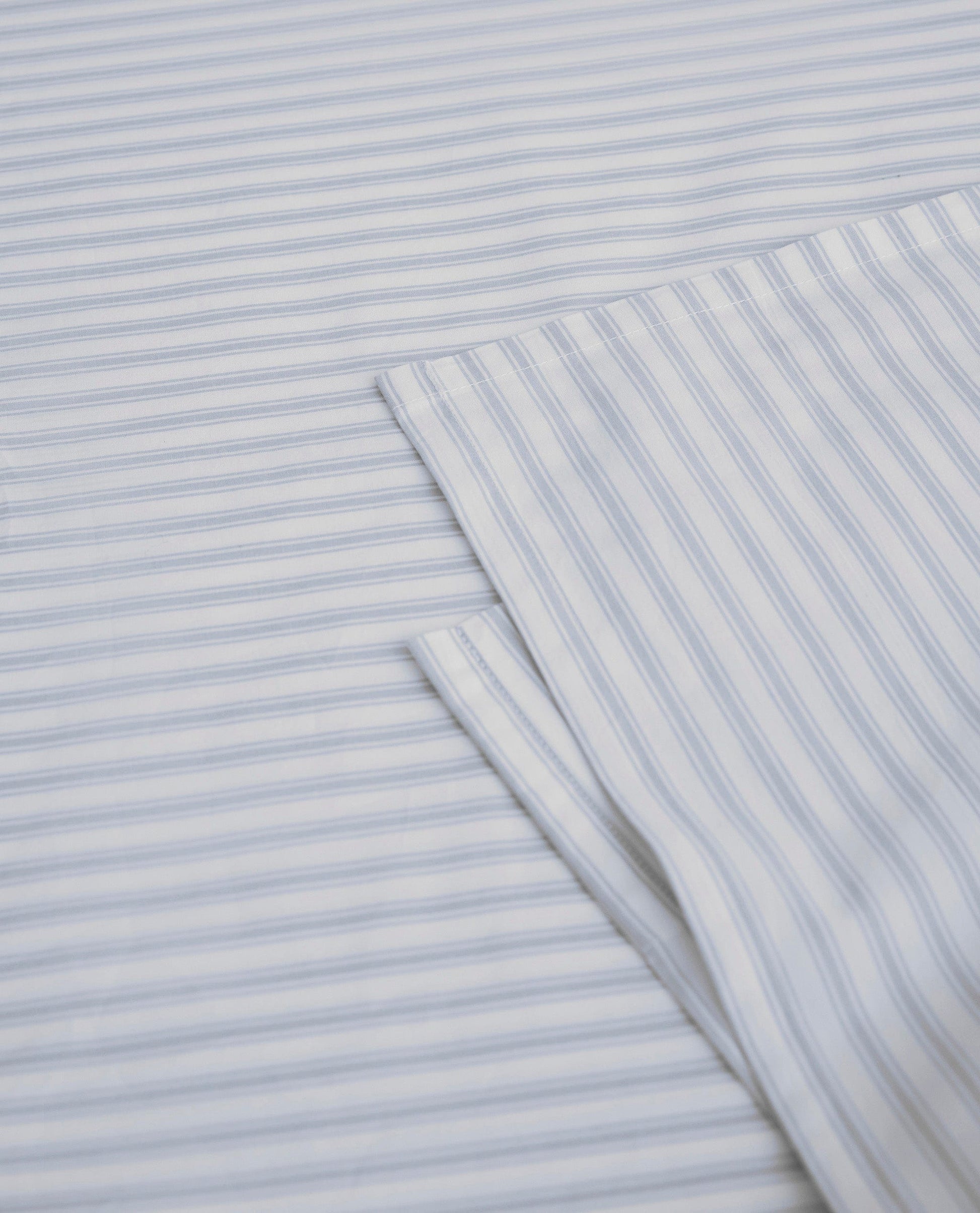Image 2 of 5 showing Rise & Fall's Crisp & Cool organic percale cotton flat bed sheet in blue ticking stripe.