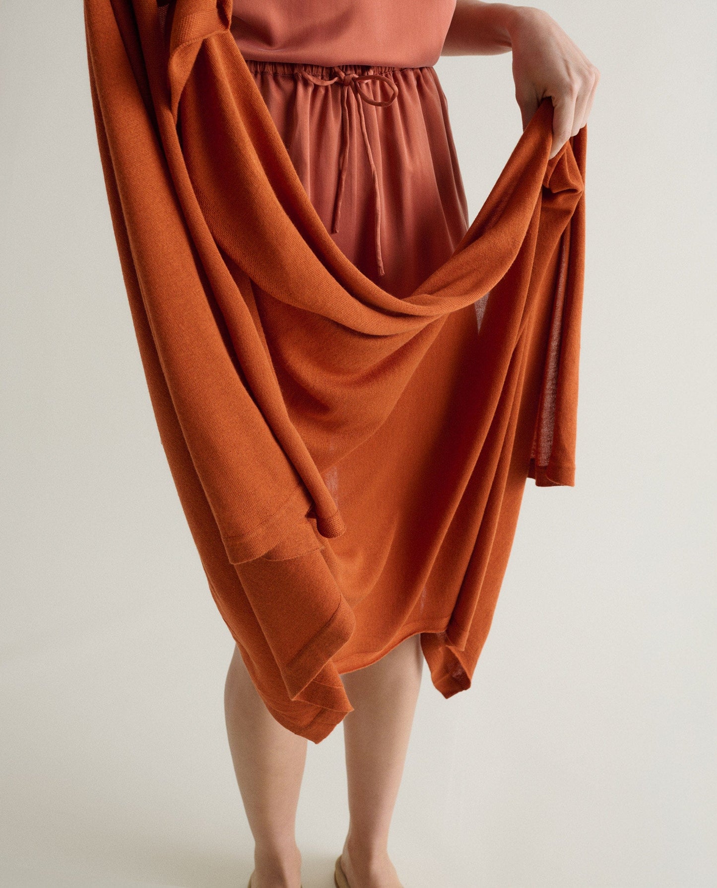 Image 2 of 6 showing woman with Rise & Fall's oversized cashmere scarf in rust.