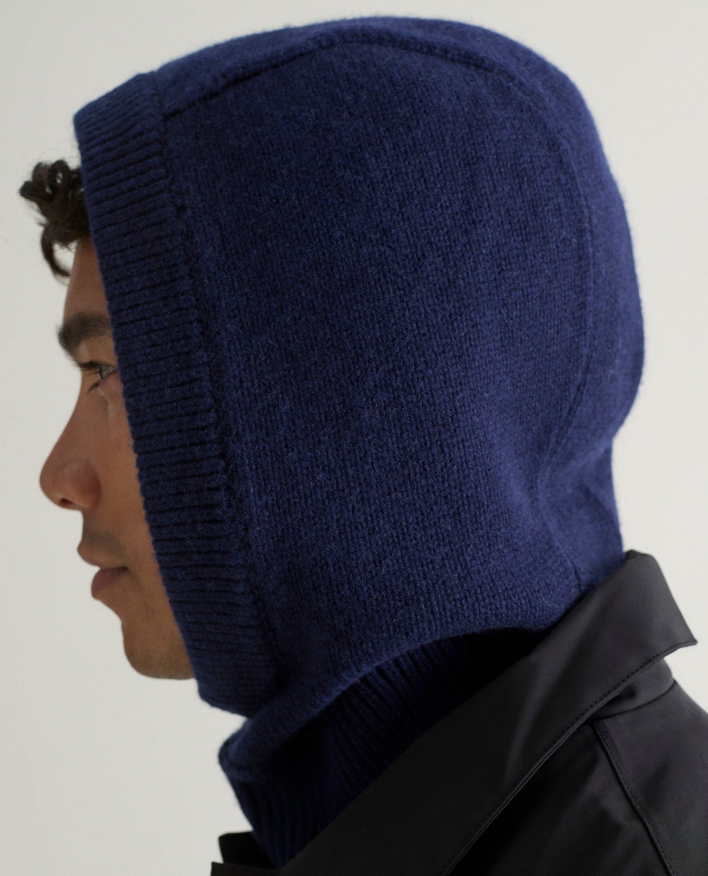 Image 3 of 3 showing side view of man wearing Rise & Fall's navy Cashmere Merino Knitted Hood.