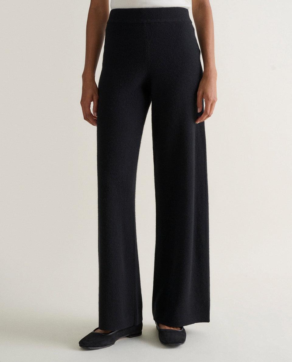 Image 3 of 4 showing woman wearing Rise & Fall's black fine cashmere wide-leg trousers with a white top.