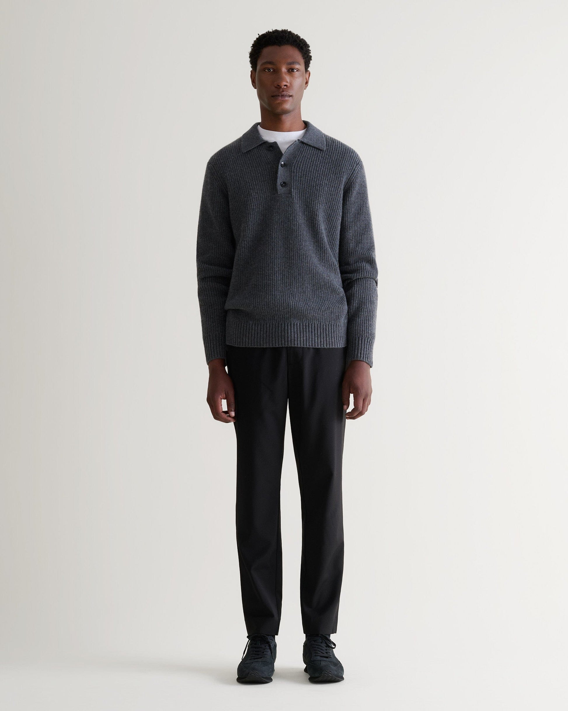 Image 3 of 5 showing man wearing Rise & Fall's graphite cashmere merino fisherman ribbed polo jumper with white T-Shirt and black trousers