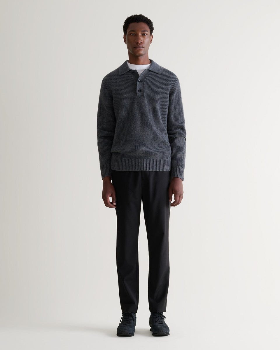 Image 3 of 5 showing man wearing Rise & Fall's graphite cashmere merino fisherman ribbed polo jumper with white T-Shirt and black trousers