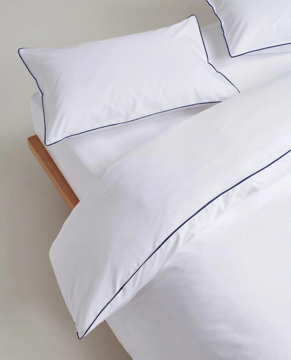 image 3 of 5 showing close up of Rise & Fall's Soft & Smooth duvet set, colour: white with navy piping, fabric: sateen cotton