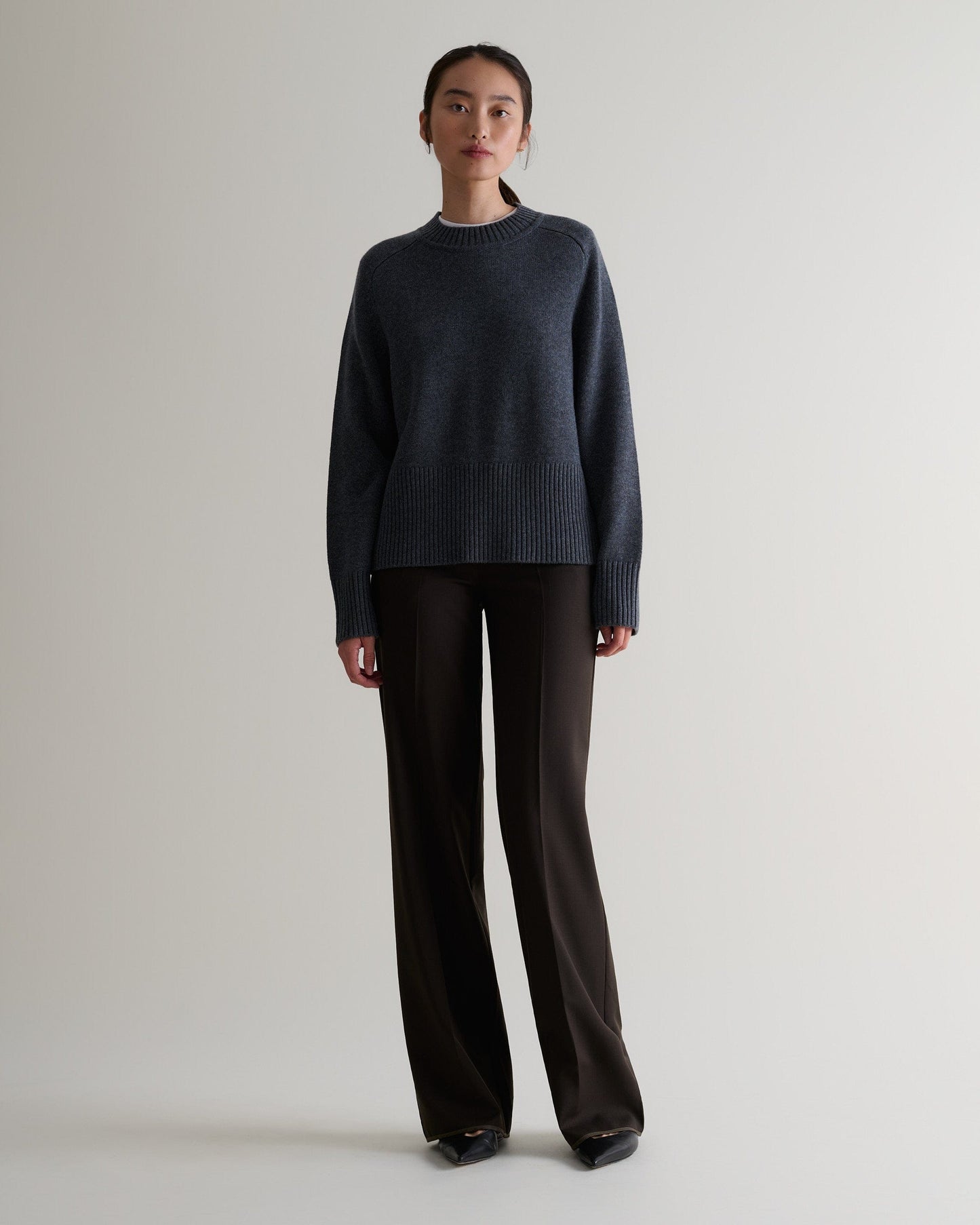 Image 3 of 5 showing woman wearing Rise & Fall graphite cashmere merino saddle sleeve crew neck jumper with chocolate silk trousers.