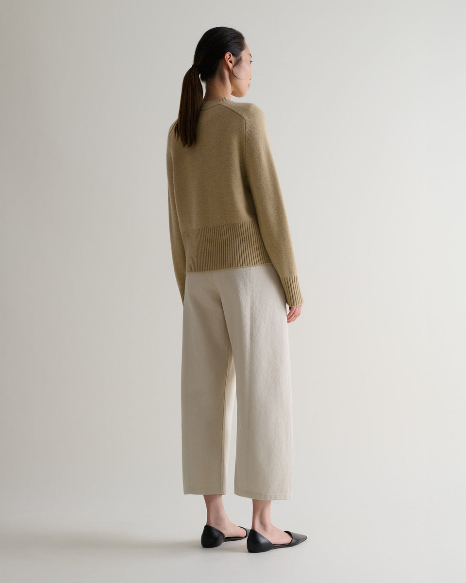 Image 3 of 5 showing back of woman wearing Rise & Fall twine cashmere merino saddle sleeve crew neck jumper with cream barrel jeans.
