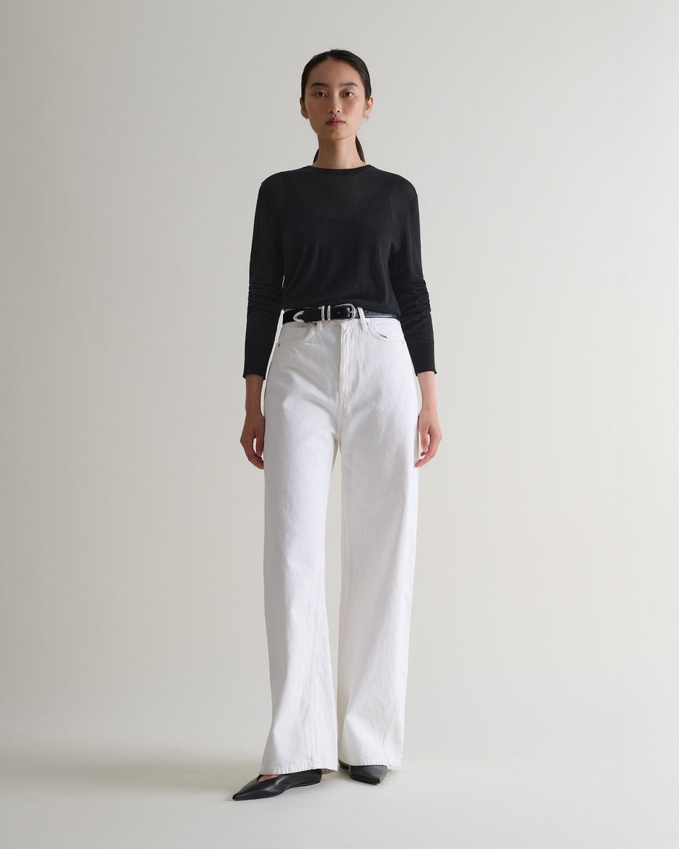 Image 3 of 5 showing woman wearing Rise & Fall's black tencel cashmere double layered crew neck jumper with white jeans, black belt.
