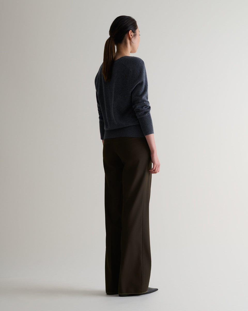 Image 3 of 5 showing back of woman wearing Rise & Fall's fine cashmere blouson cardigan, colour: graphite.