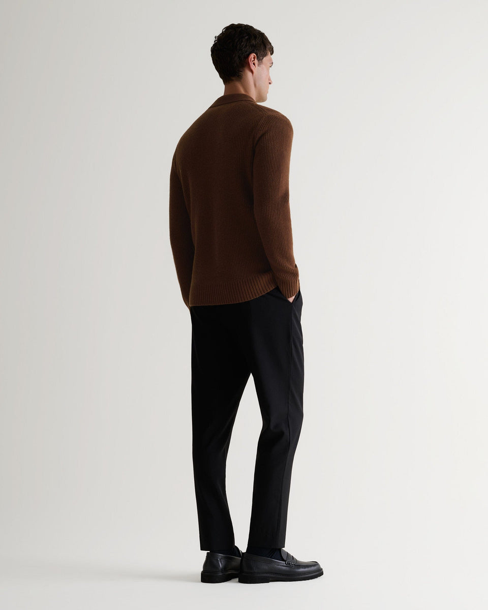 Image 3 of 6 showing back of man wearing Rise & Fall's brown cashmere merino fisherman ribbed buttoned polo with black trousers leather shoes.