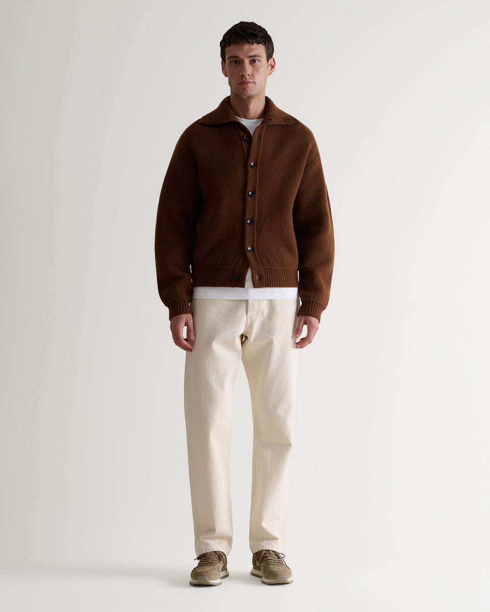 Image 3 of 6 of man wearing Rise & Fall's burl brown cashmere merino stand neck ribbed jumper with cream jeans and beige suede trainers. 