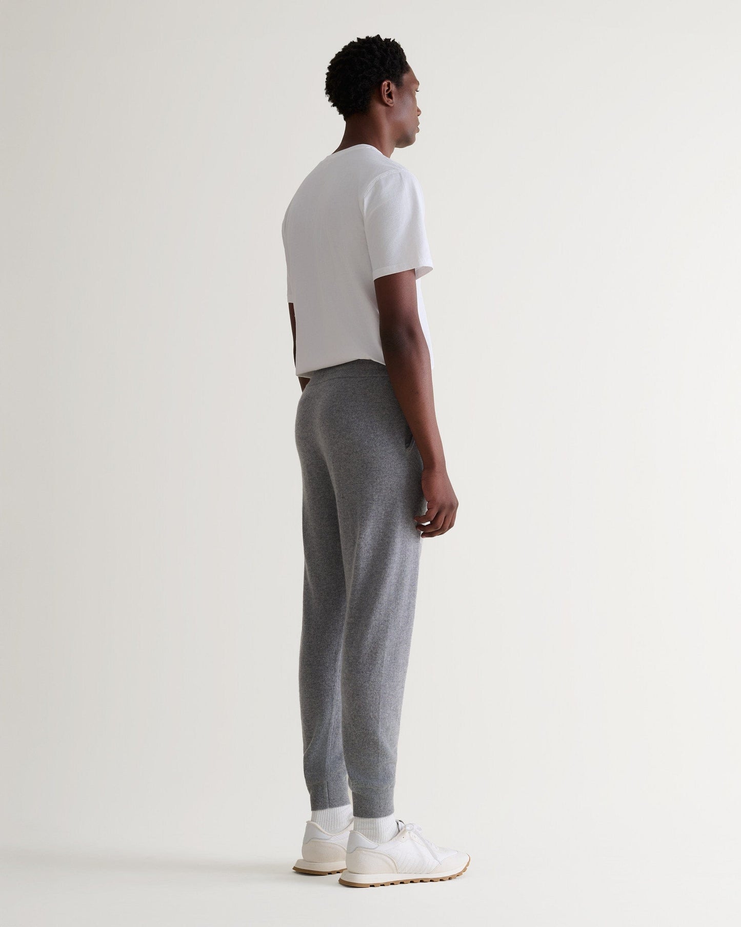 Image 3 of 6 showing man wearing Rise & Fall's fine cashmere joggers, grey, back view.
