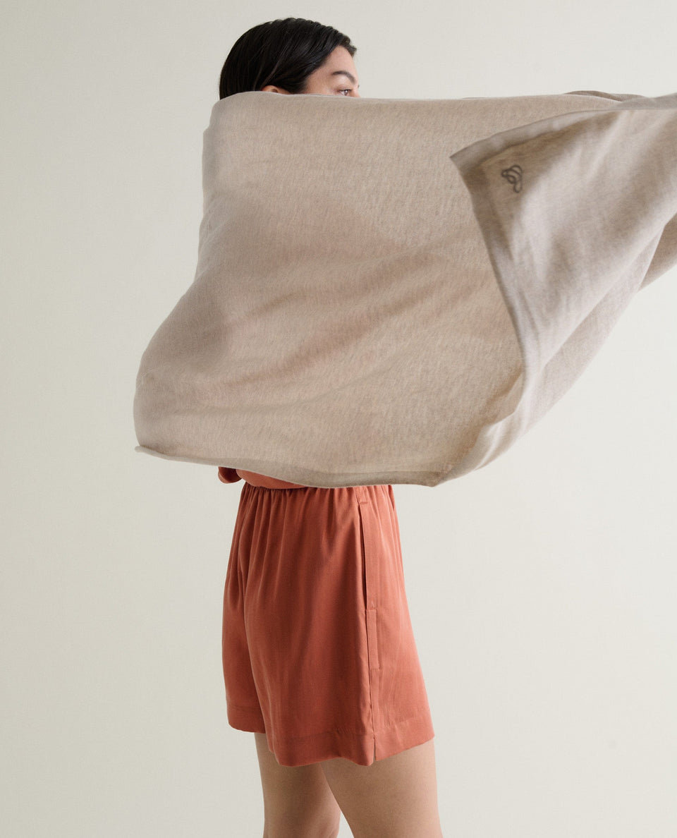 Image 3 of 6 showing woman wrapping Rise & Fall's oversized cashmere scarf around shoulders, colour: light beige.