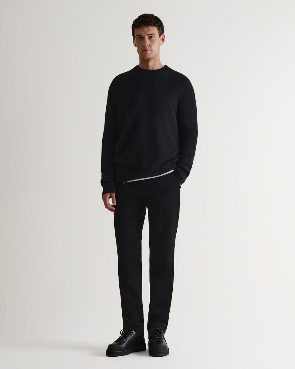 Image 3 of 7 showing man wearing Rise & Fall's Finest Cashmere Mid-Weight Crew Neck Jumper in black with tailored black trousers.