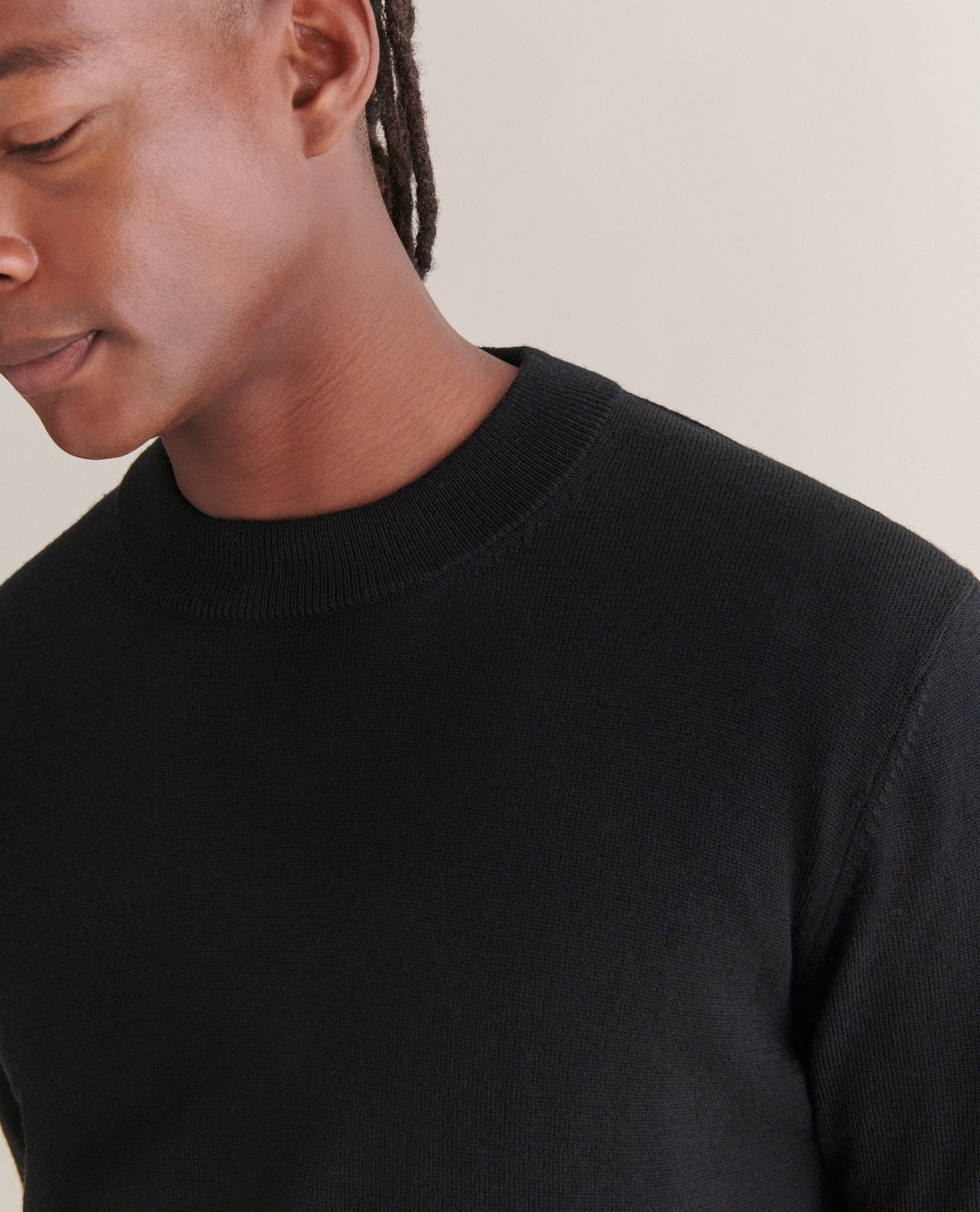 Image 4 of 4 showing close up of man wearing Rise & Fall's merino mid-weight crew neck jumper in black.