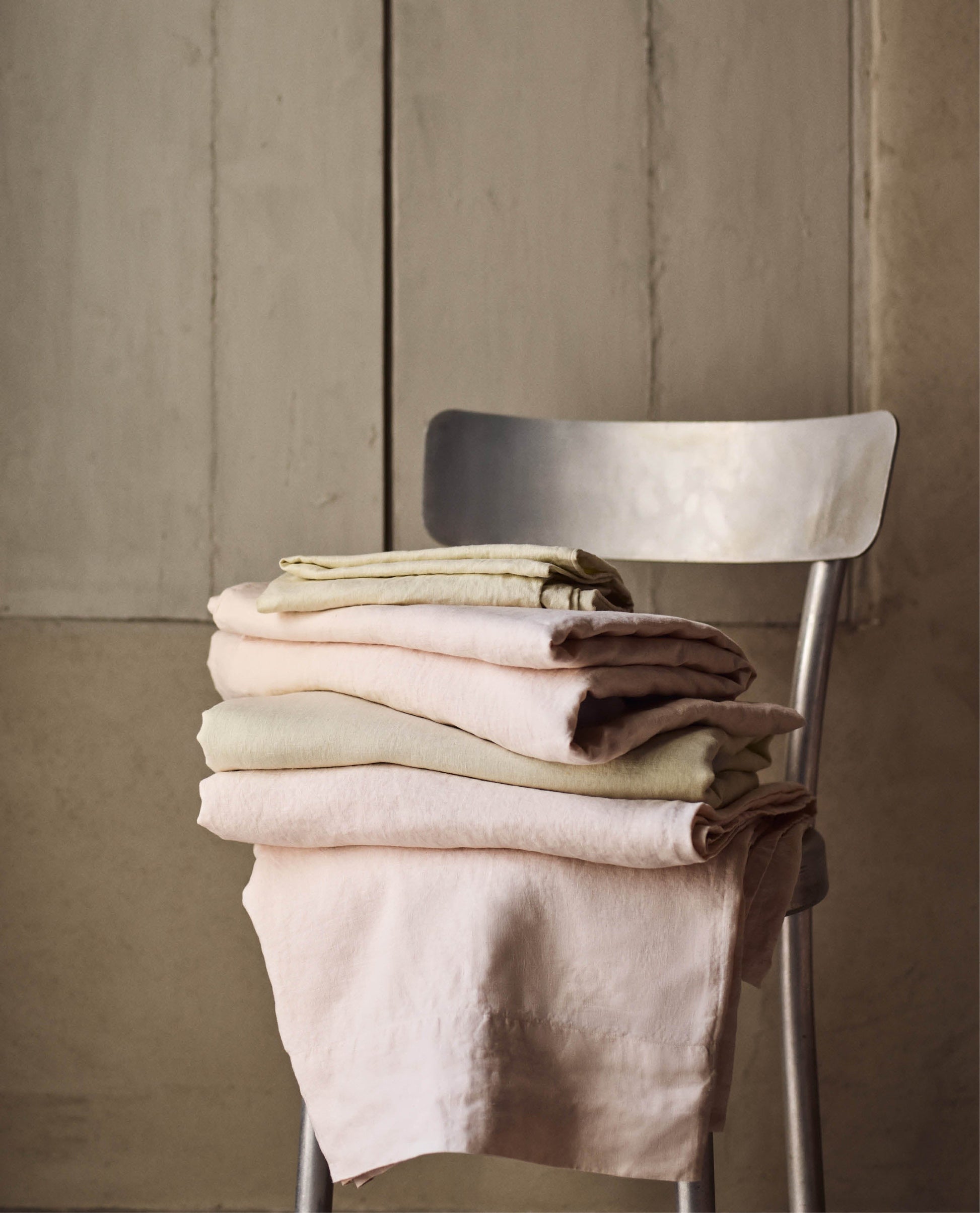 Image 4 of 4 showing pile of Rise & Fall's House of Grey linen flat bed sheets in celery and peach.