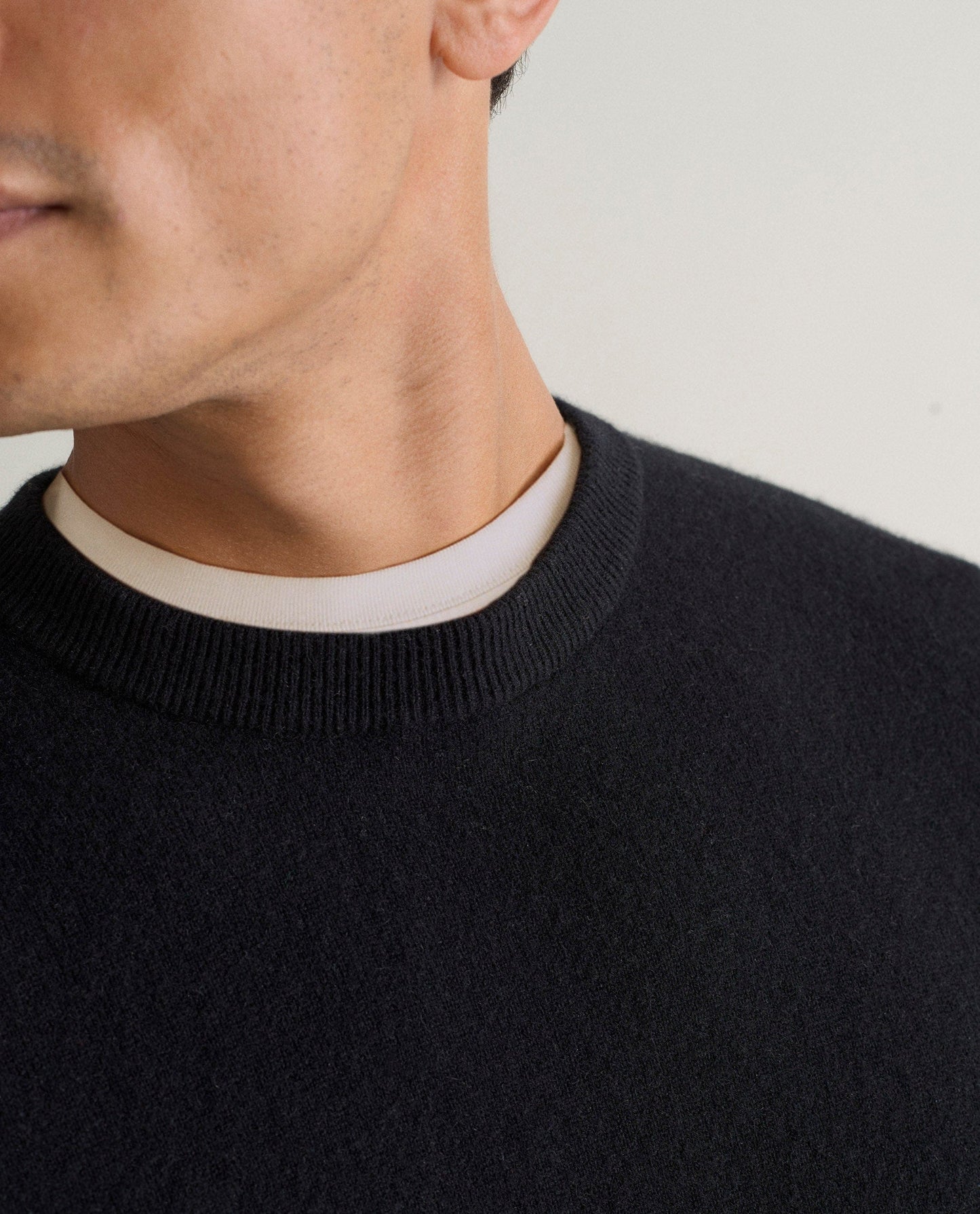 Image 4 of 5 showing close up of man wearing Rise & Fall's black finest cashmere sweatshirt over white t-shirt.