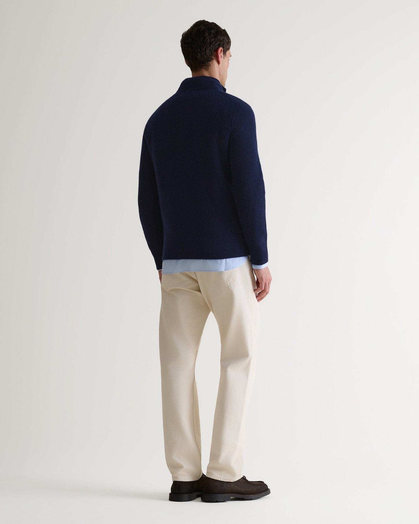 Image 4 of 5 showing back of man wearing Rise & Fall's Cashmere Merino Fishermans Rib 1/4 Zip Jumper in navy.