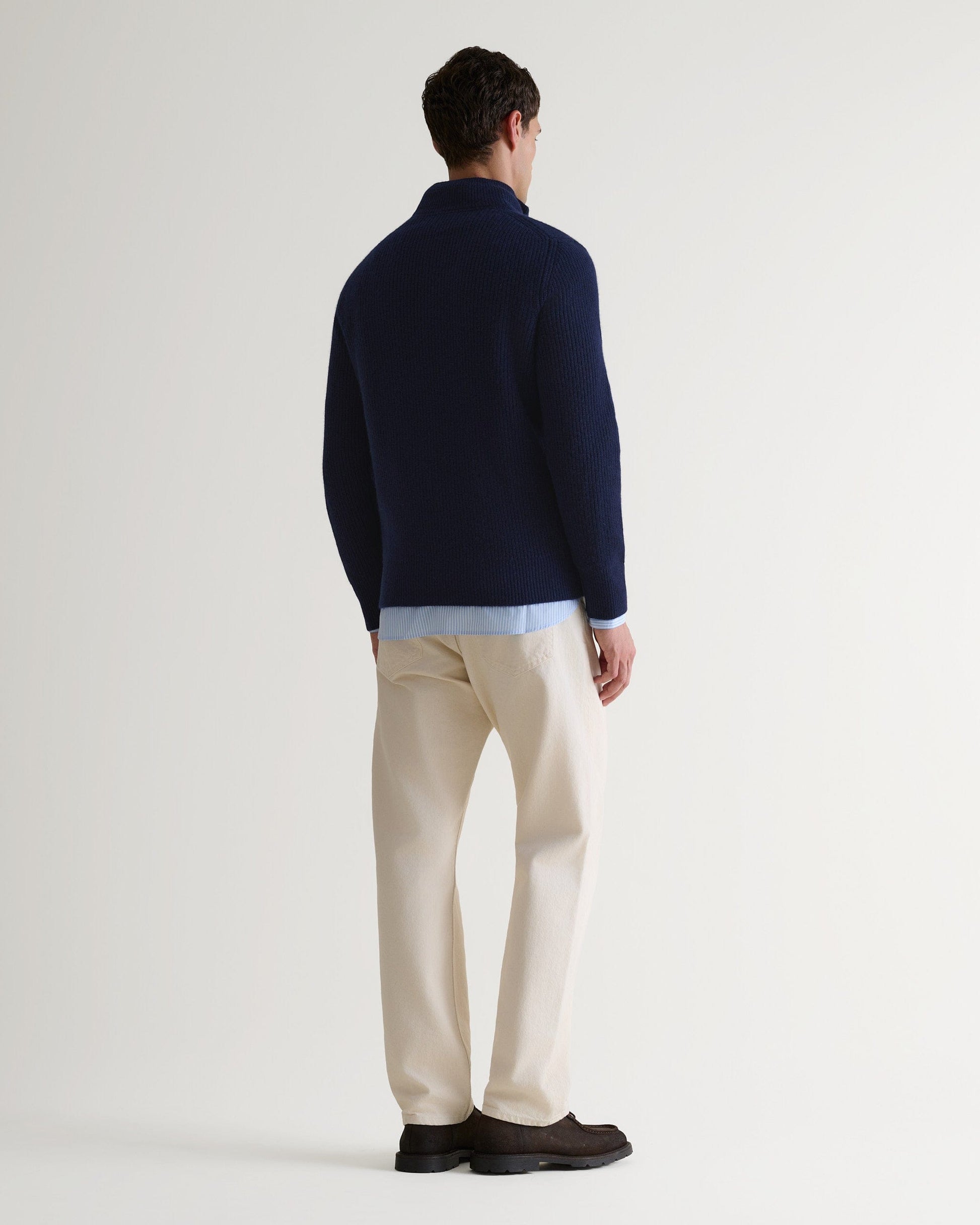 Image 4 of 5 showing back of man wearing Rise & Fall's Cashmere Merino Fishermans Rib 1/4 Zip Jumper in navy.