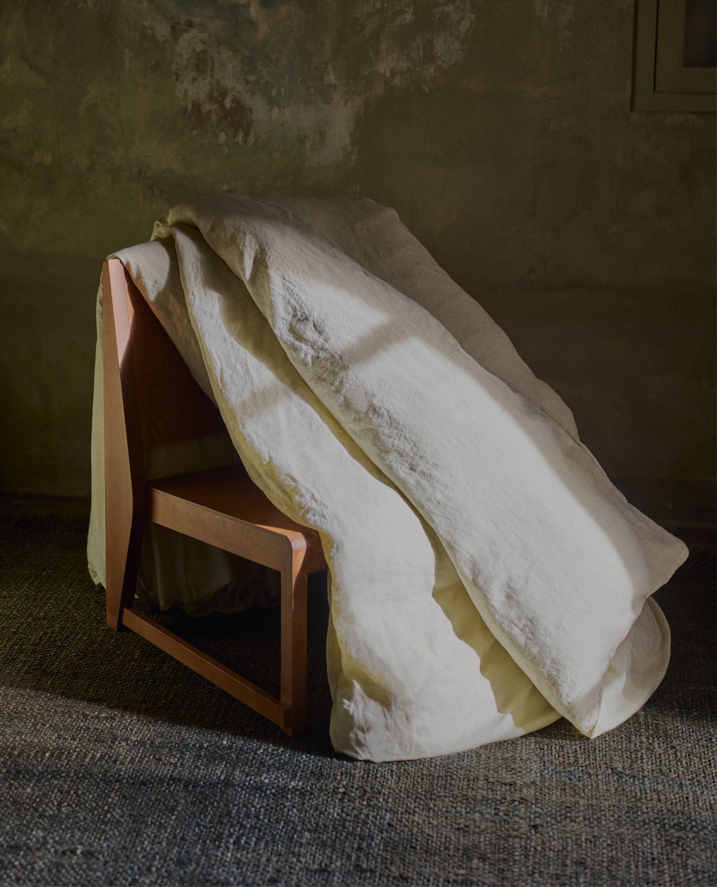image 4 of 5 showing Rise & Fall's Relaxed & Refined linen duvet cover draped over wooden chair, fabric: European flax, colour: celery