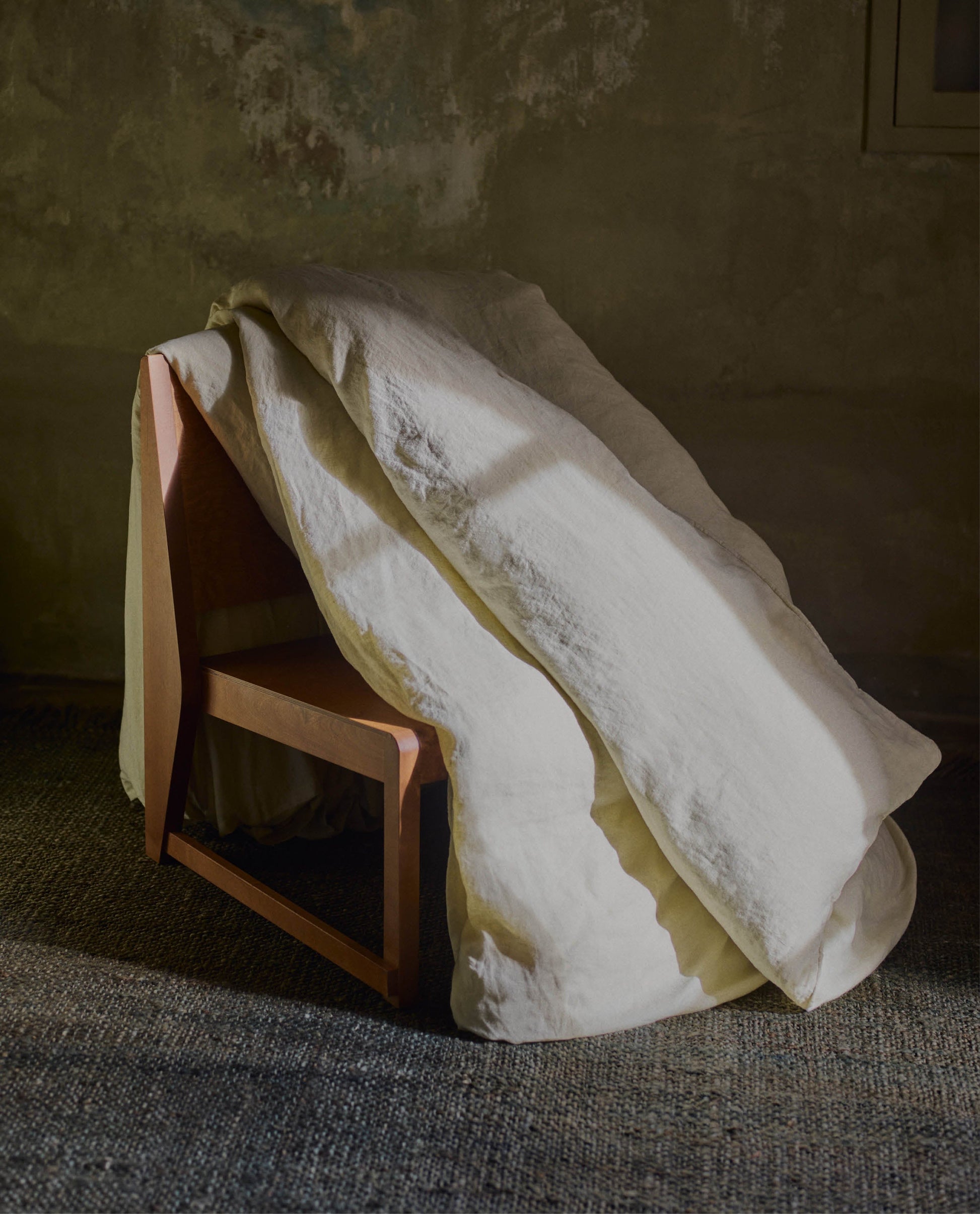 image 4 of 5 showing Rise & Fall's Relaxed & Refined linen duvet cover draped over wooden chair, fabric: European flax, colour: celery