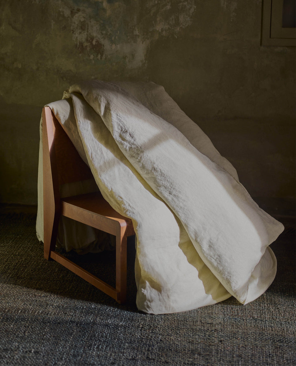 image 4 of 5 showing Rise & Fall's Relaxed & Refined linen duvet cover draped over wooden chair, fabric: European flax, colour: celery