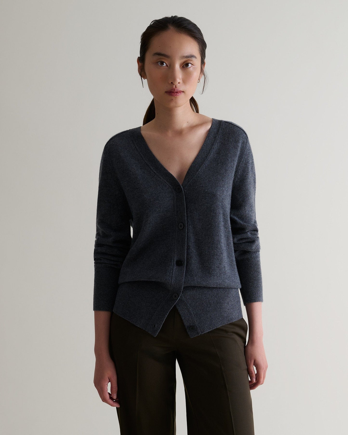 Image 4 of 5 showing woman wearing Rise & Fall's graphite fine cashmere blouson cardigan with brown trousers.