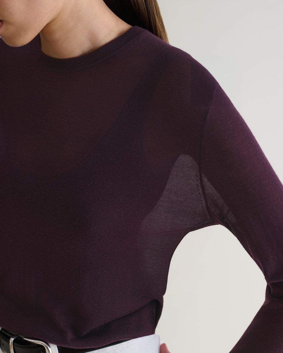 Image 4 of 5 showing close up of a woman wearing Rise & Fall's oxblood tencel™ cashmere double layered crew neck jumper with white jeans and black belt. 