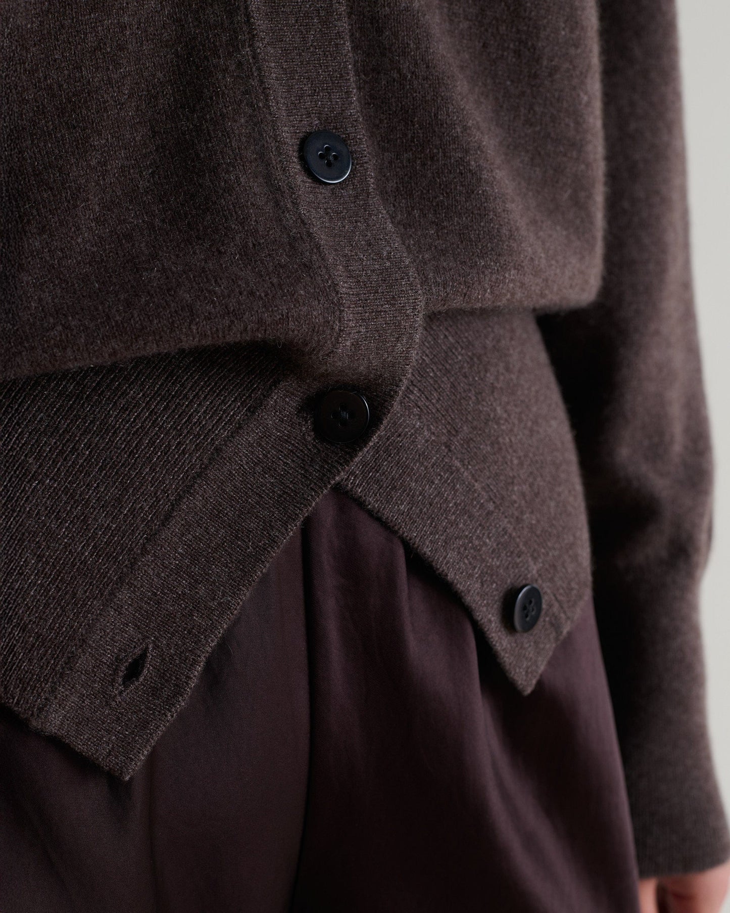 Image 4 of 6 showing close up Rise & Fall's chocolate fine cashmere blouson cardigan with silk brown trousers.