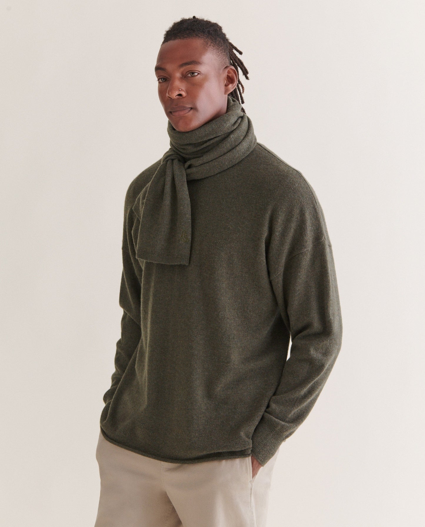 Image 5 of 5 showing man wearing Rise & Fall's finest cashmere mid-weight crew neck jumper in forest green with matching scarf and cream trousers.