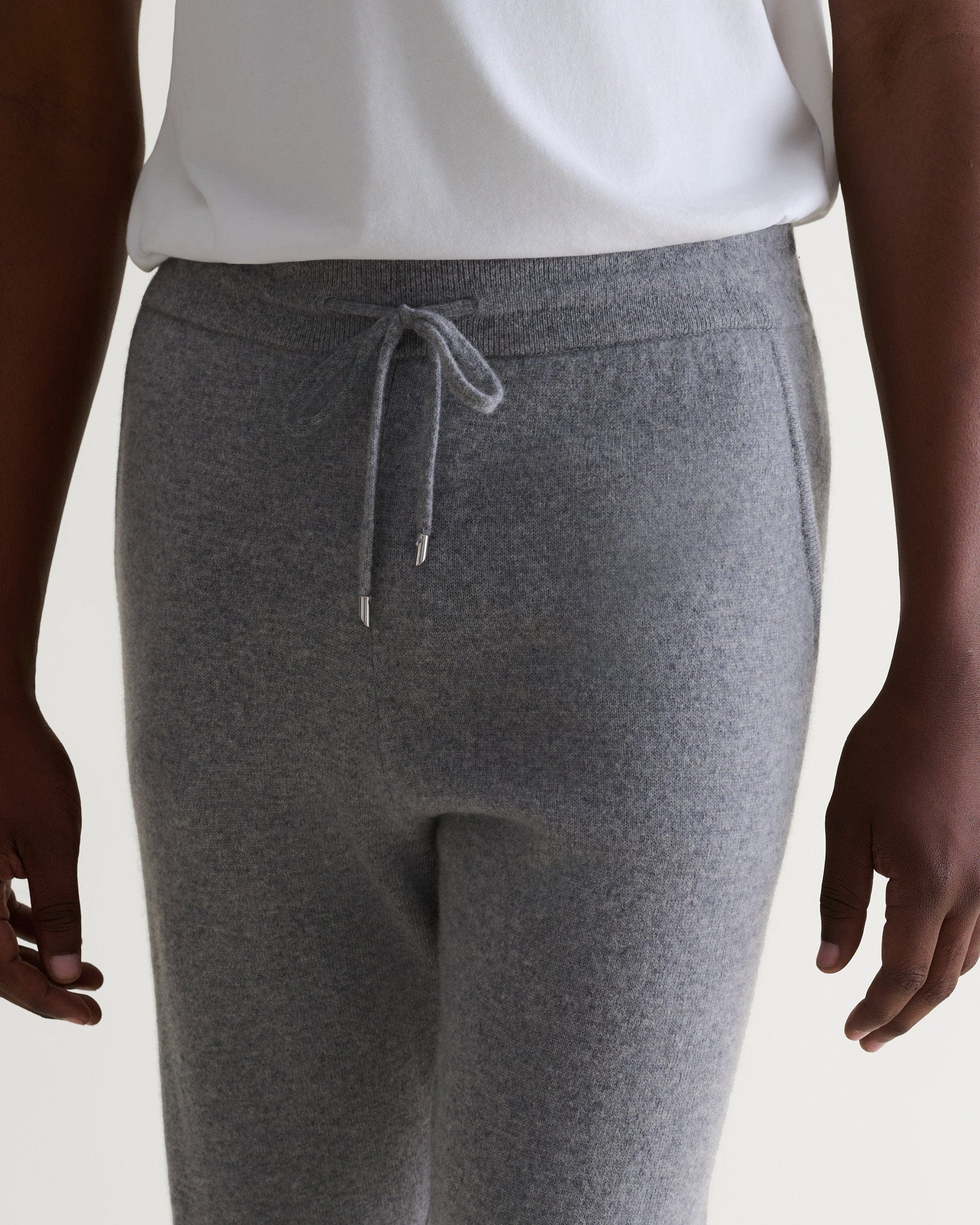 Image 5 of 6 showing man wearing Rise & Fall's fine cashmere joggers, grey, close up.