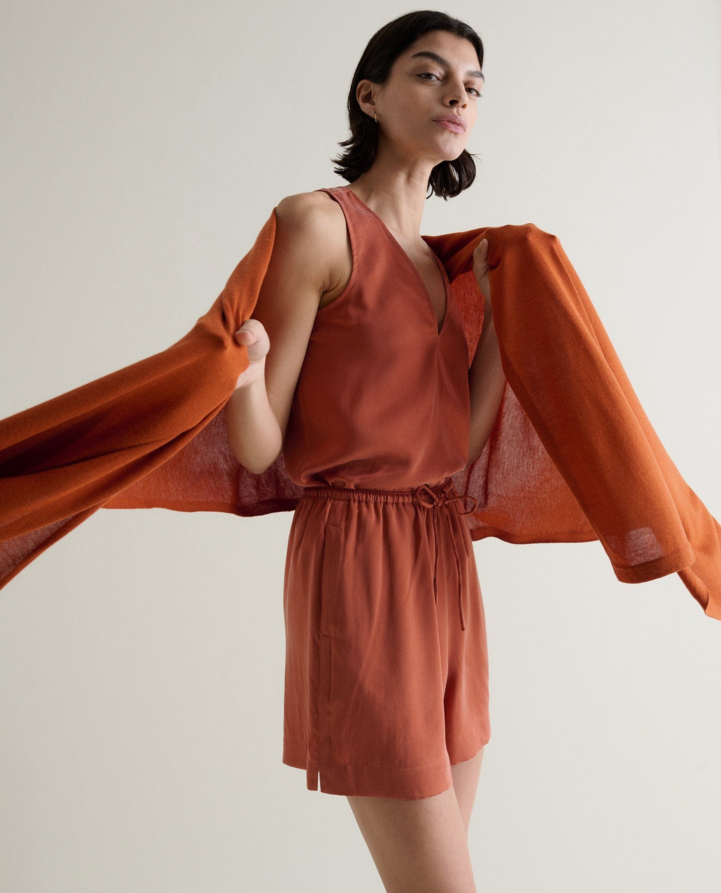 Image 5 of 6 showing woman drapping Rise & Fall's rust coloured oversized cashmere scarf over shoulders.