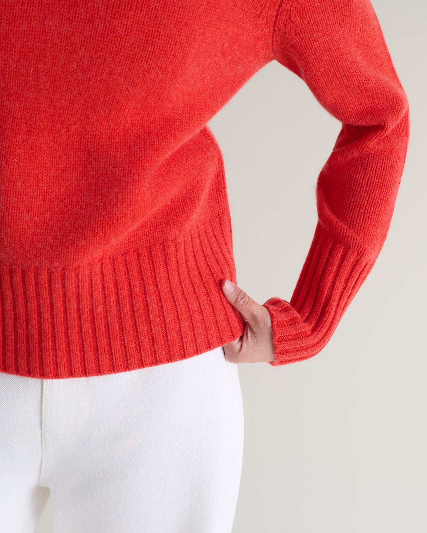 Image 6 of 6 showing close up of Rise & Fall's poppy red cashmere merino saddle sleeve crew neck jumper with white jeans.