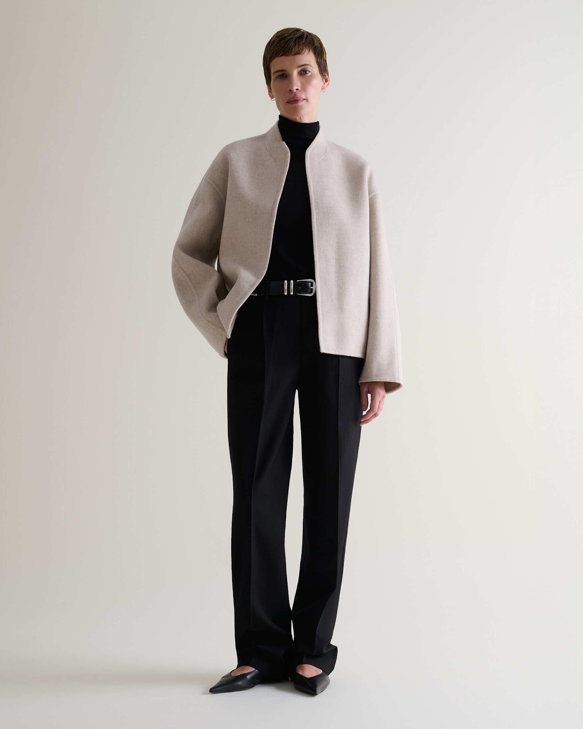 Image 9 of 9 showing woman wearing Rise & Fall's twine cashmere wool double faced jacket with black trousers.