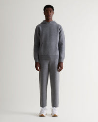 Full length front view of man wearing grey cashmere merino double-faced hoodie with matching tracksuit bottoms-white-trainers.