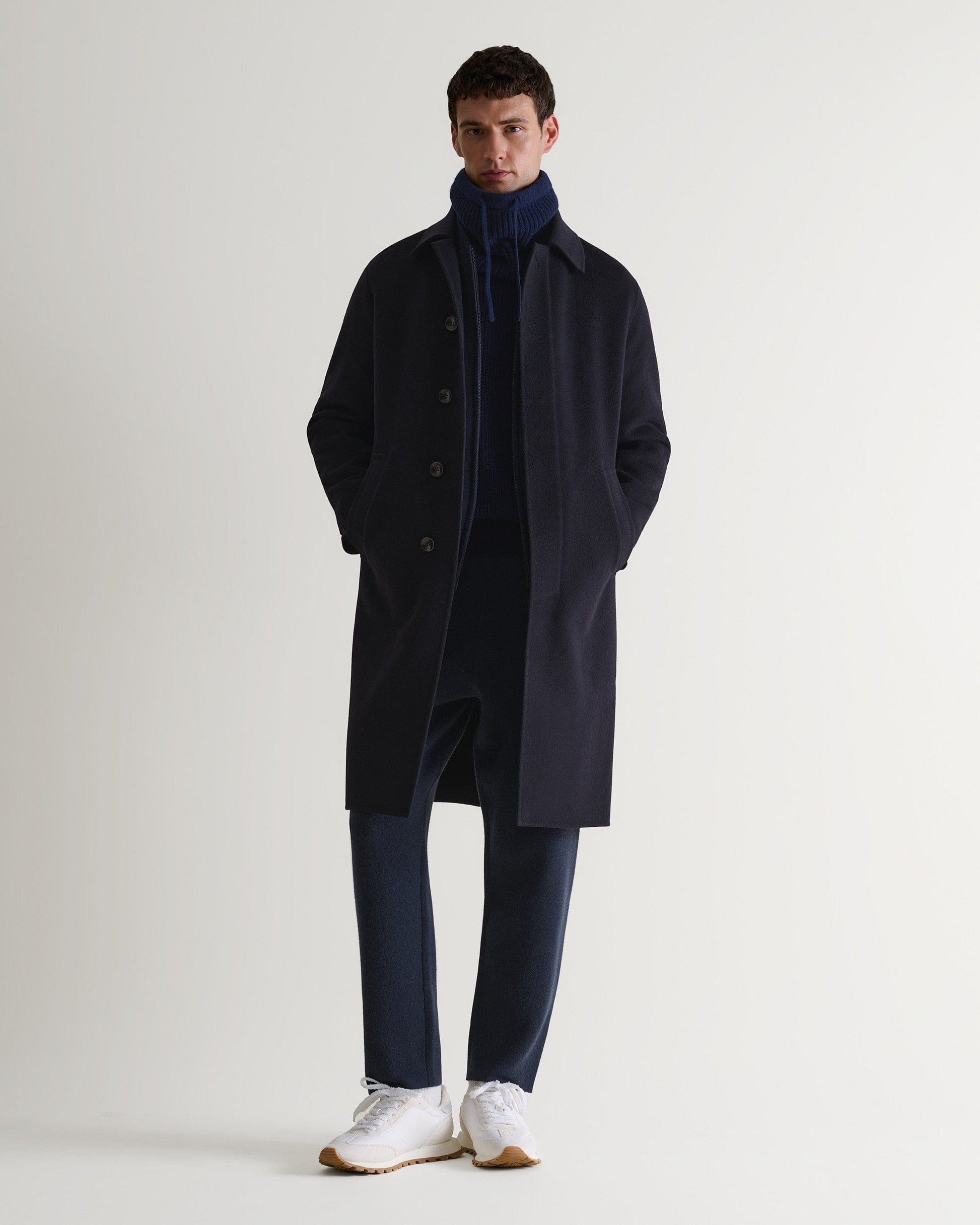 Full portrait view of man wearing indigo cashmere merino drawstring snood with navy overcoat and trousers