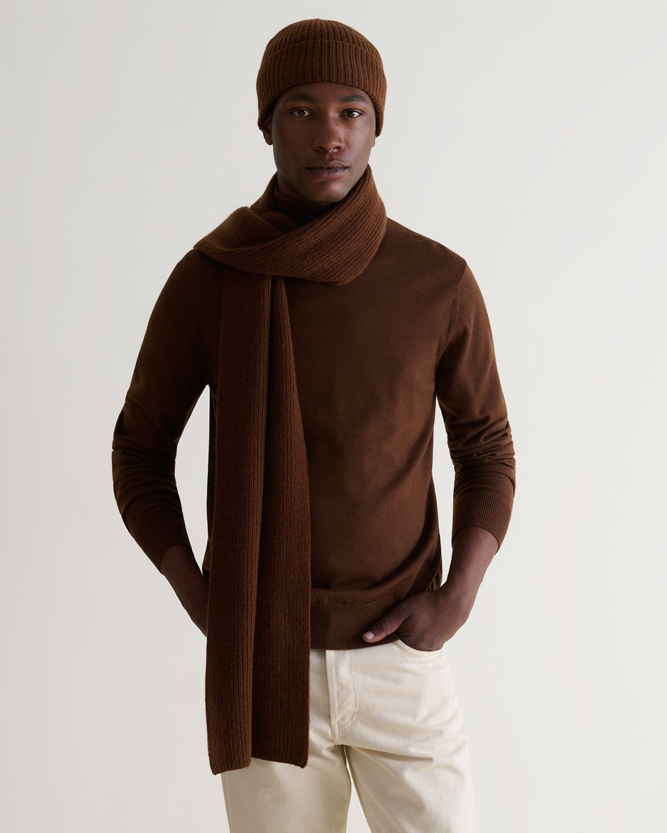 Man wearing Rise & Fall's burl brown cashmere merino ribbed scarf with matching coloured jumper and beanie and cream jeans