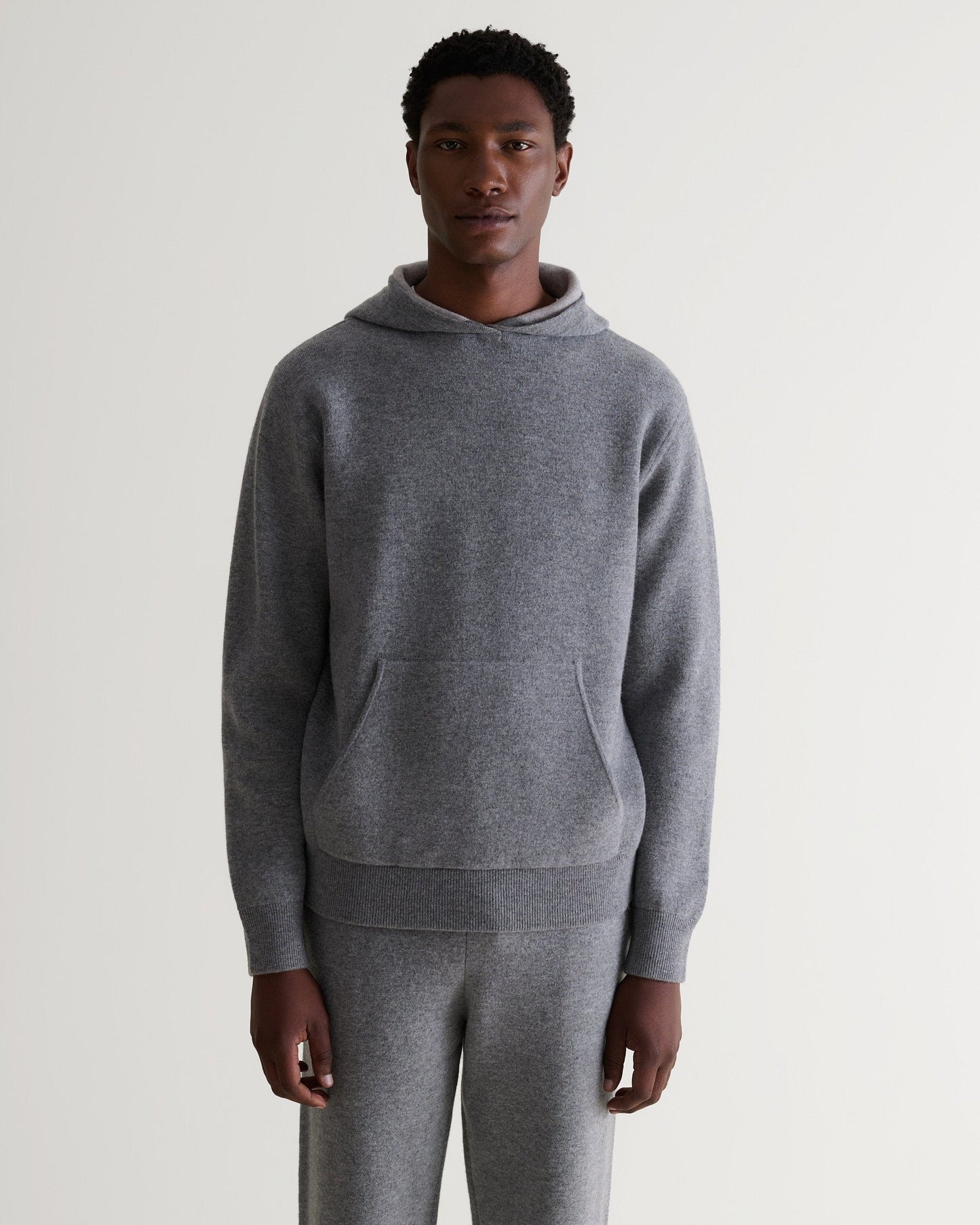 Front view of man wearing Rise & Fall's grey cashmere merino double-faced hoodie and matching joggers.