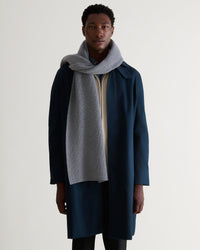 Man wearing Rise & Fall's medium grey cashmere merino ribbed scarf with cream jumper and navy coat