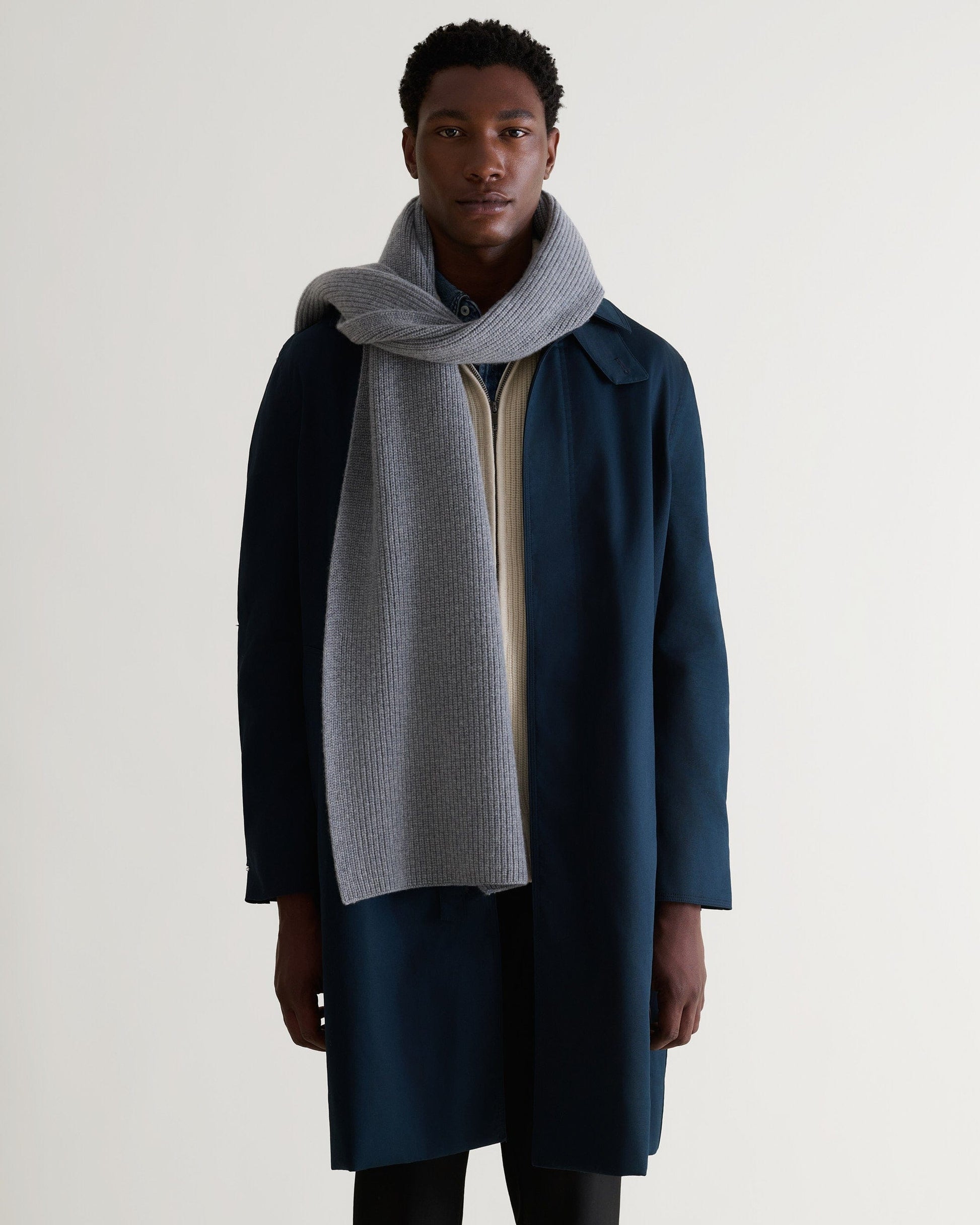 Man wearing Rise & Fall's medium grey cashmere merino ribbed scarf with cream jumper and navy coat