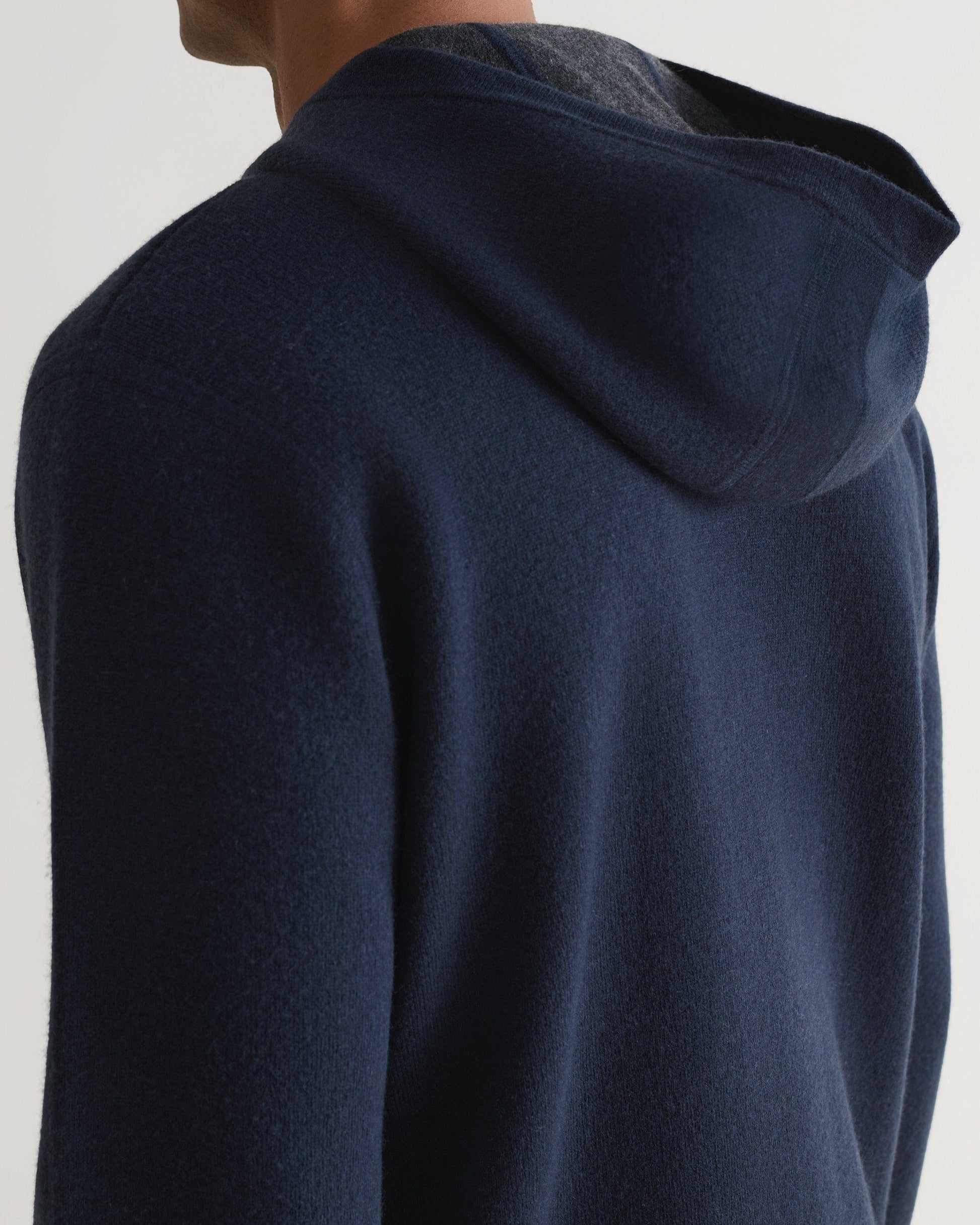 Back view of man wearing Rise & Fall's navy cashmere merino double-faced hoodie.