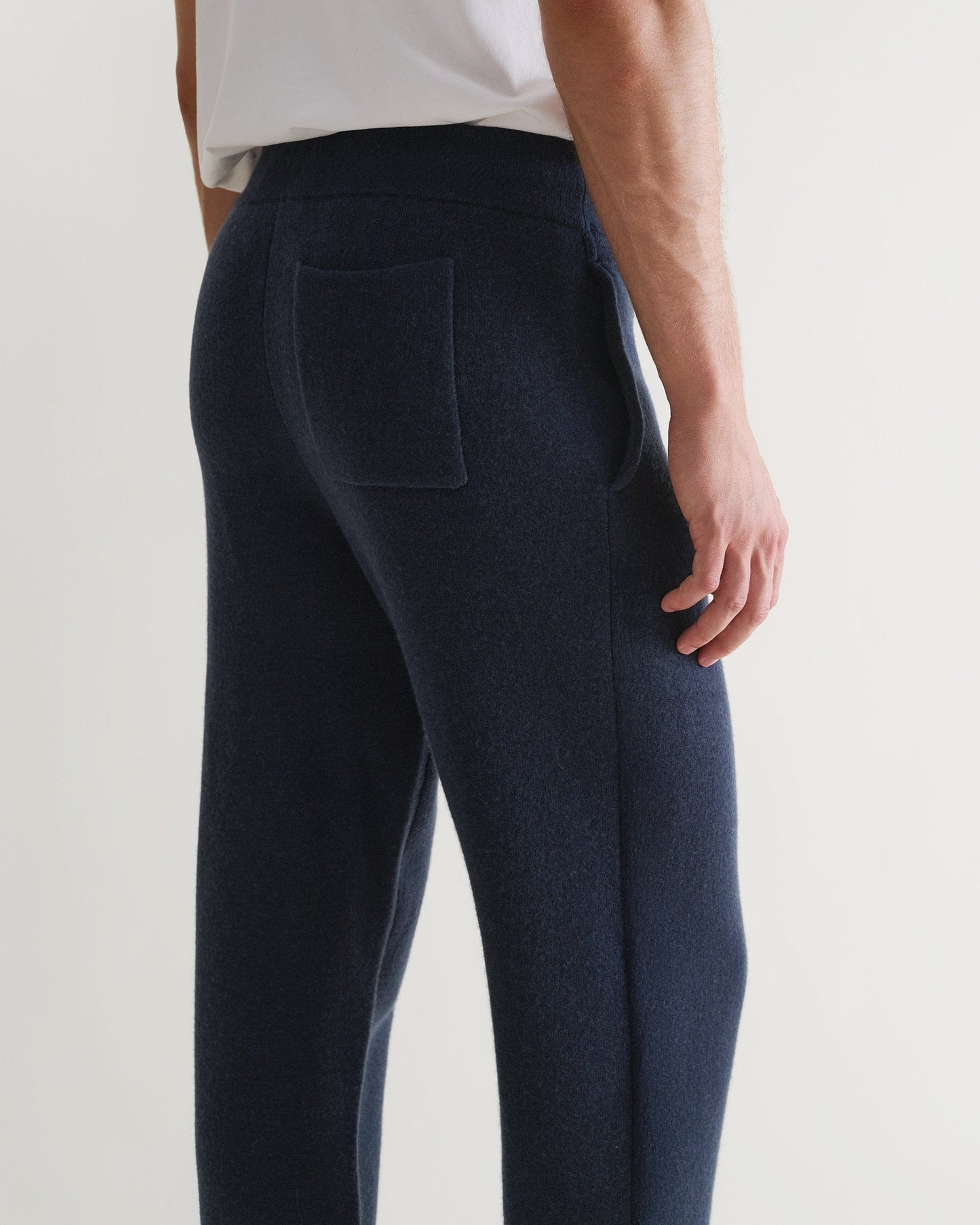 Side view of man wearing Rise & Fall's navy cashmere merino double-faced joggers with white T-shirt.
