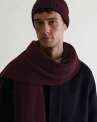 Close up of man wearing Rise & Fall's oxblood cashmere merino ribbed scarf with matching coloured beanie and navy wool coat