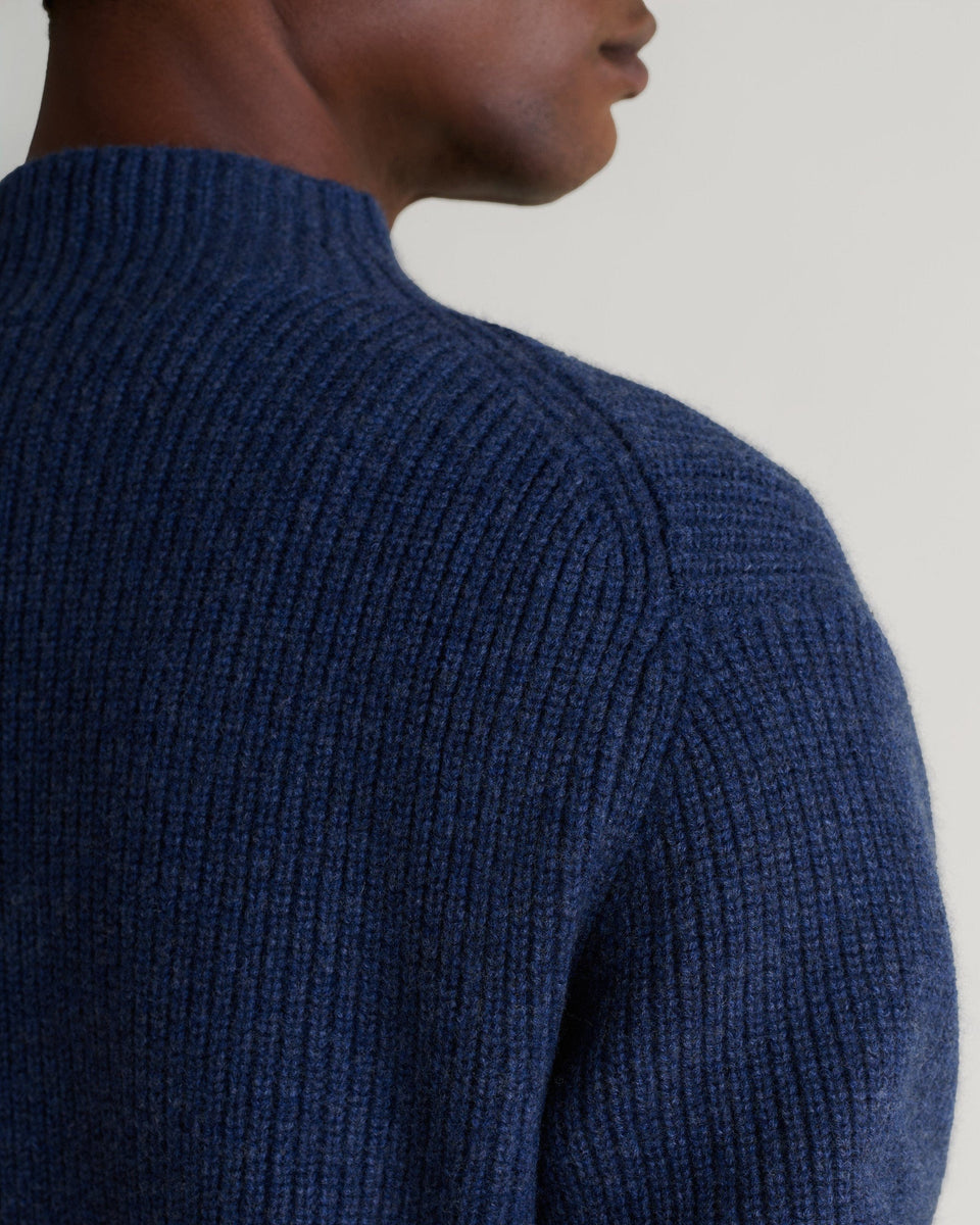 Man wears Rise & Fall's indigo blue cashmere merino stand neck jumper. A close up of shoulder. 