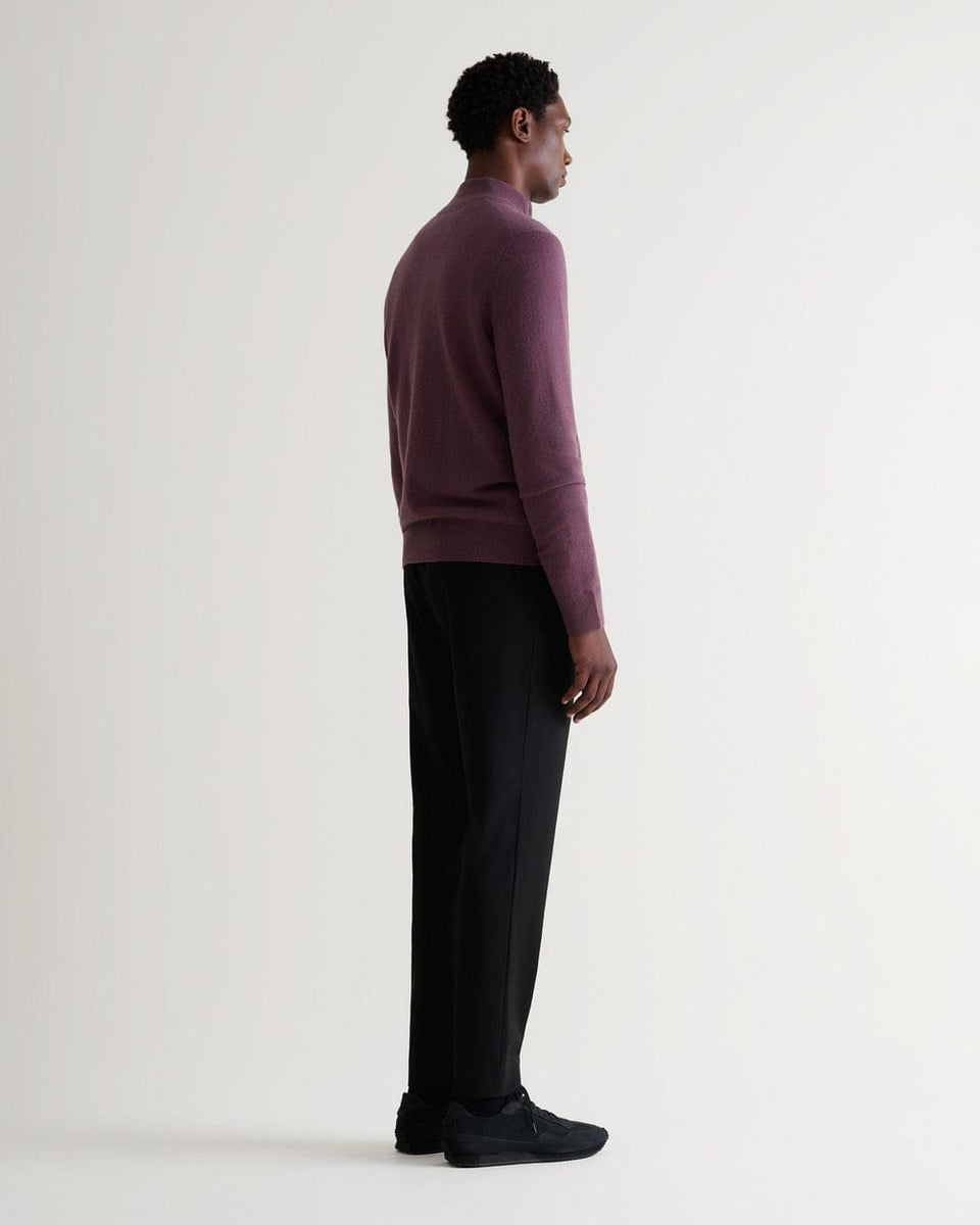 Full length side view of man wearing Rise & Fall's smoky lilac finest cashmere 1/4 zip jumper. Worn with black trousers.