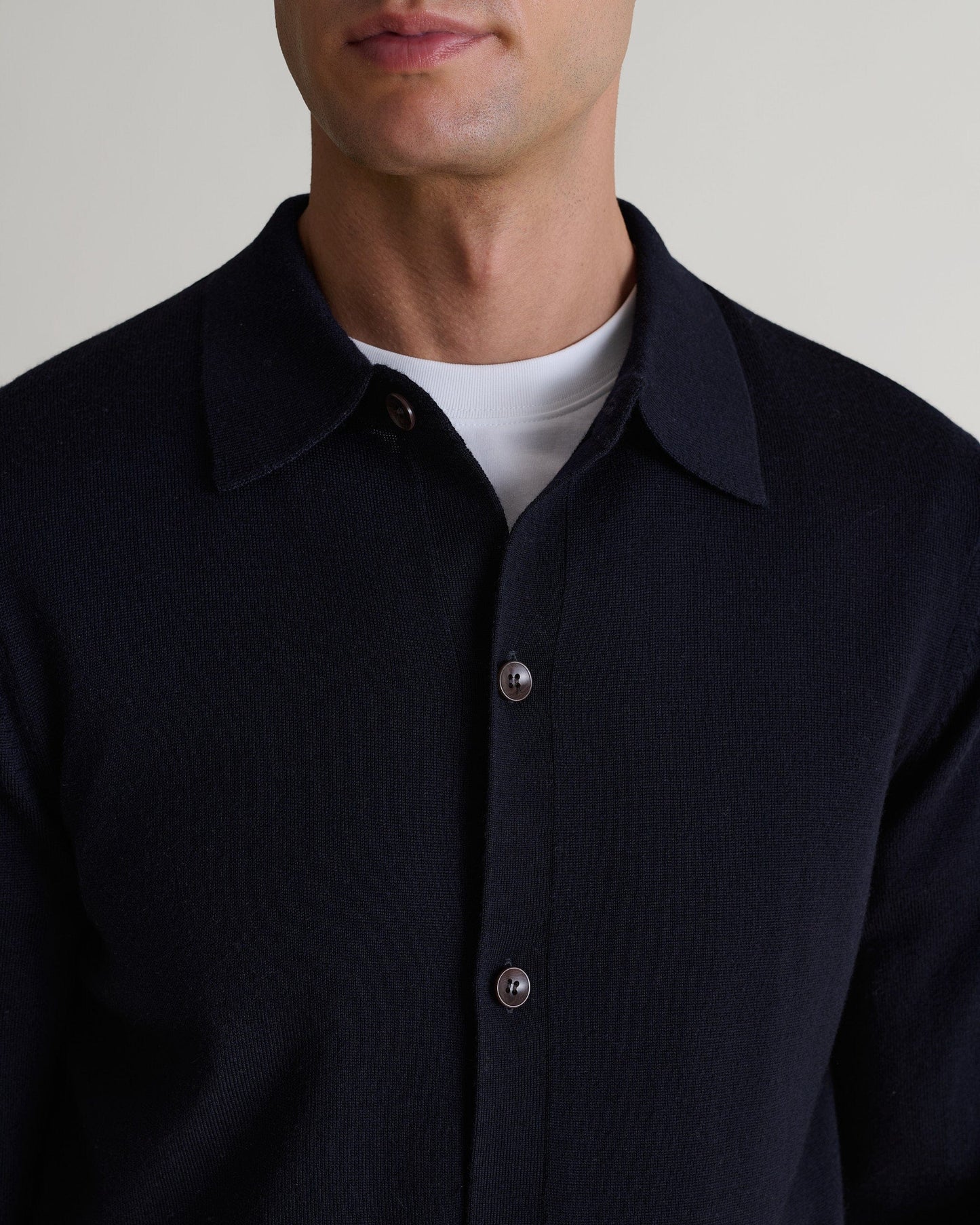 Close up of man wearing Rise & Fall's navy fine merino knit shirt. Worn with a white crew neck T-shirt.
