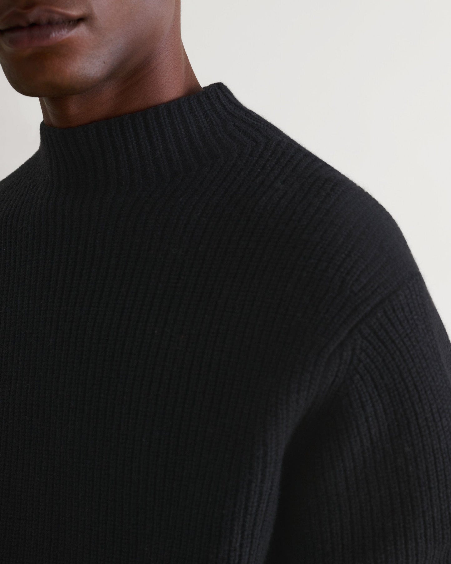 Close up top half of Rise & Fall's black cashmere merino stand neck jumper.