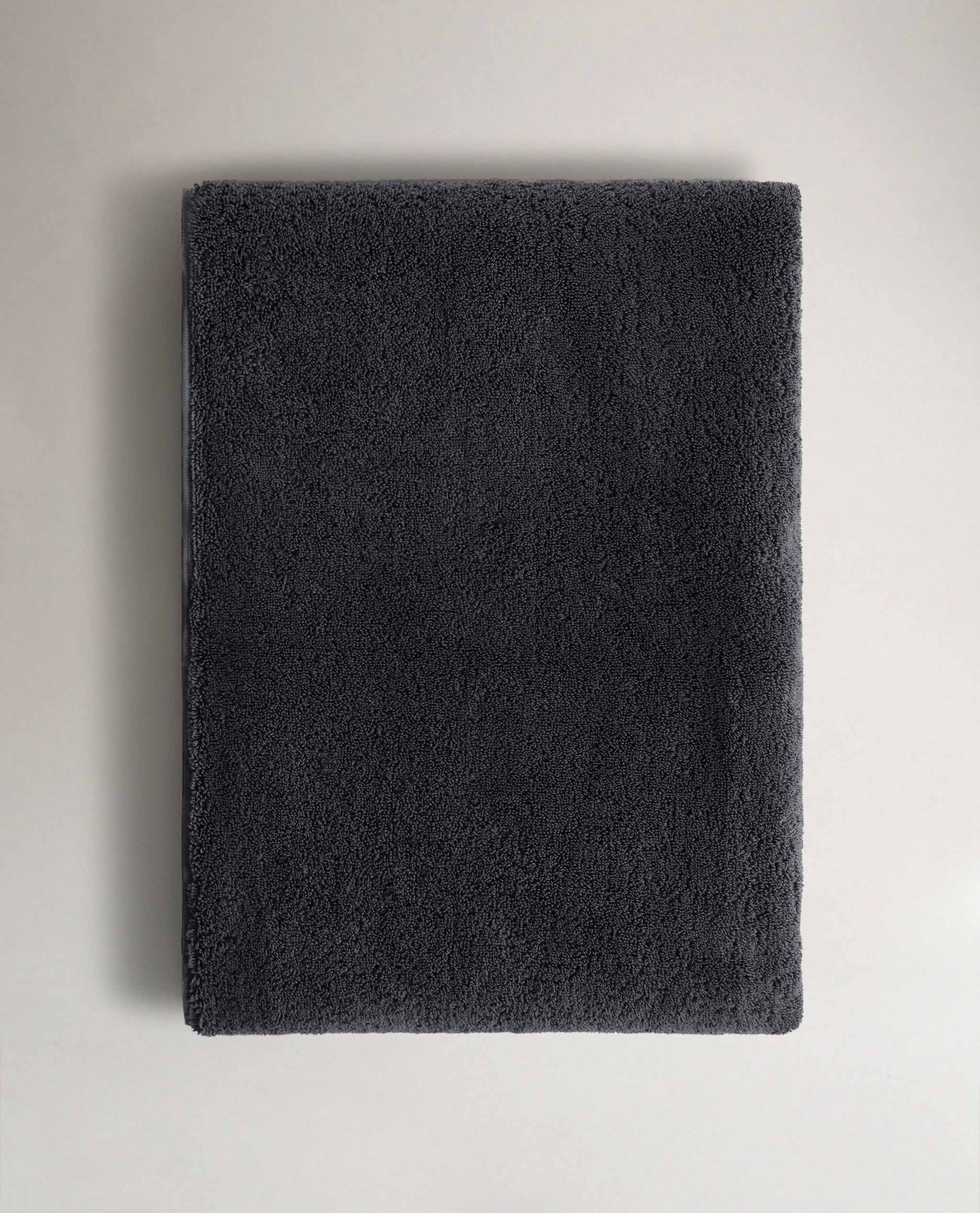 Rise & Fall's charcoal Turkish cotton hand towel lying on top of matching bath towel