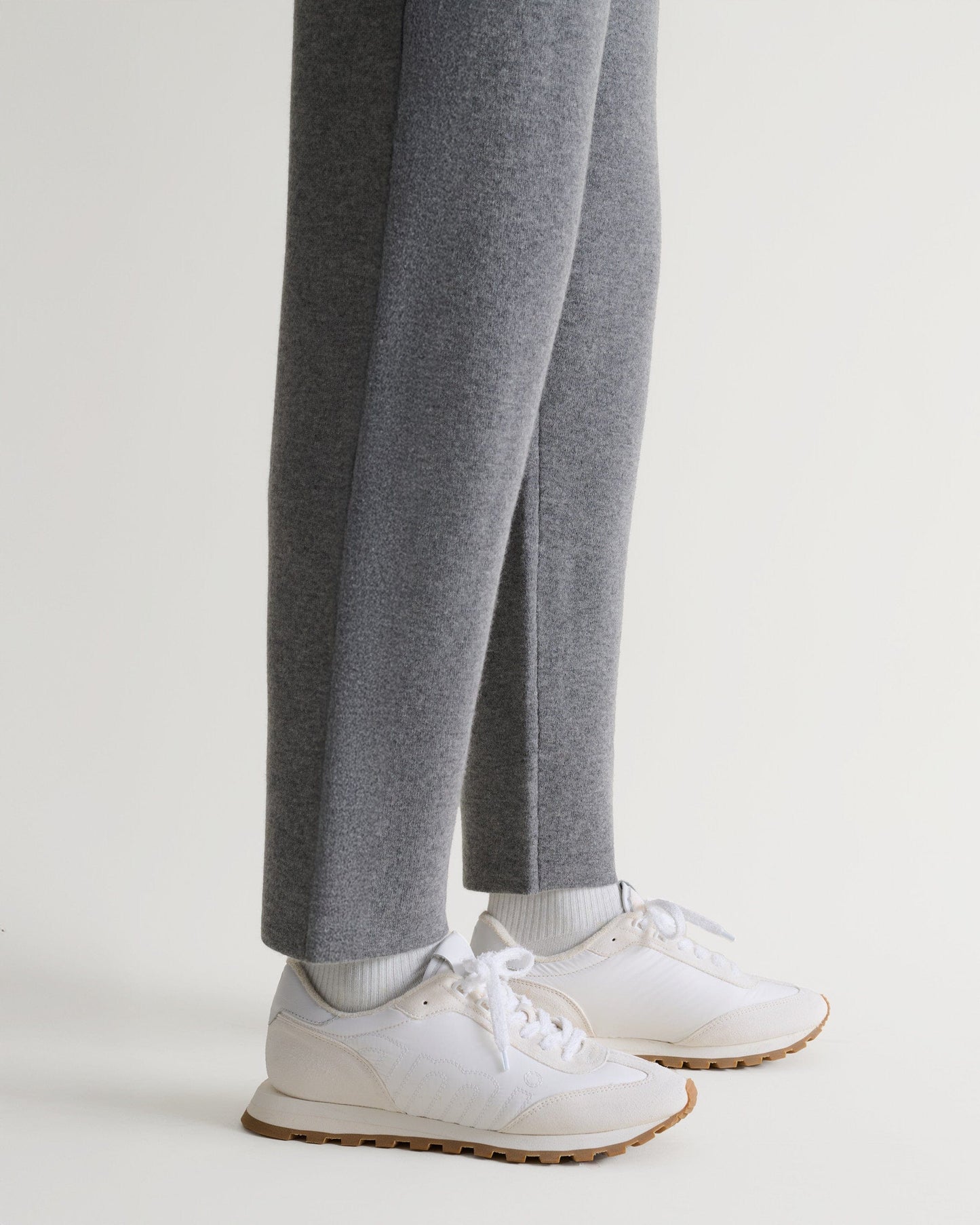 Bottom side view of Rise & Fall's grey cashmere merino double-faced joggers with white trainers. 