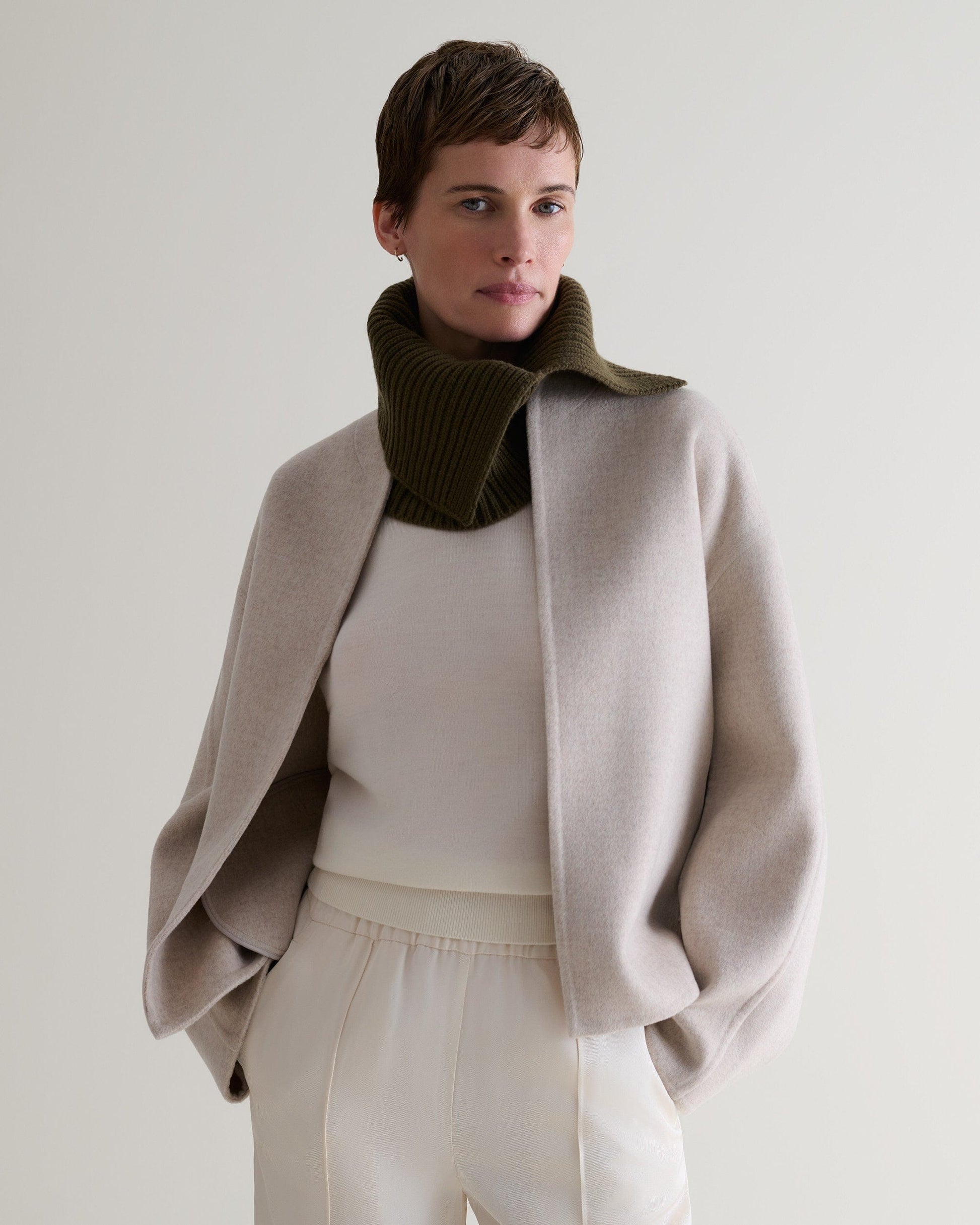 Rise & Fall cashmere merino ribbed collar in military green worn between a cream jumper and a light grey jacket